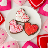 Chocolate heart-shaped Valentine's Day sugar cookies with red, pink and white royal icing and sprinkles