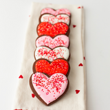 Chocolate heart-shaped Valentine's Day sugar cookies with red, pink and white royal icing and sprinkles