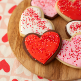 Vanilla and chocolate heart-shaped sugar cookies with red, pink and white royal icing and sprinkles